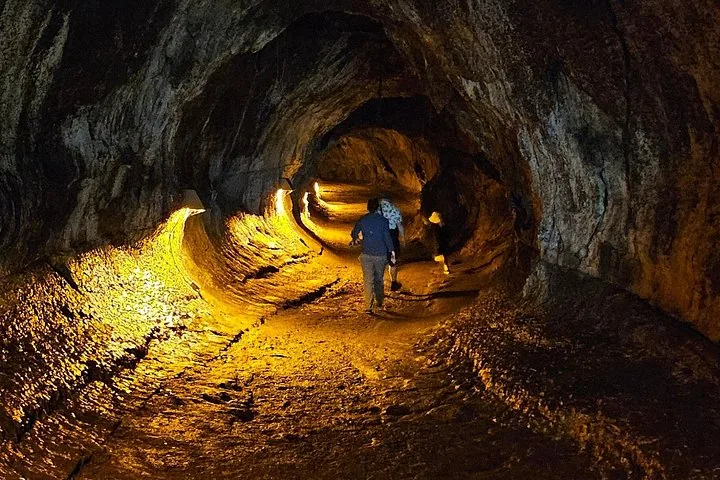 People walking through an illuminated lava tube in Hawaii.